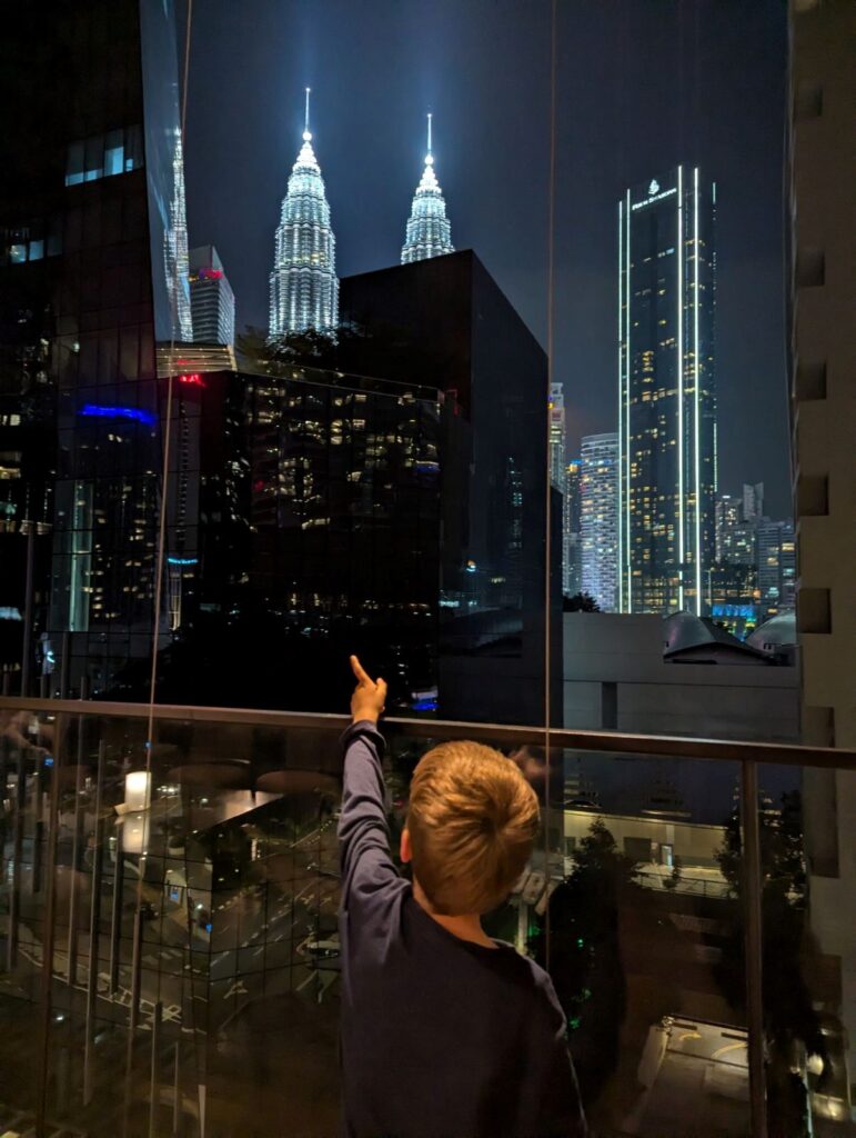 Kleiner Junge steht vor einer Skyline und zeigt begeistern mit dem Finger da drauf.