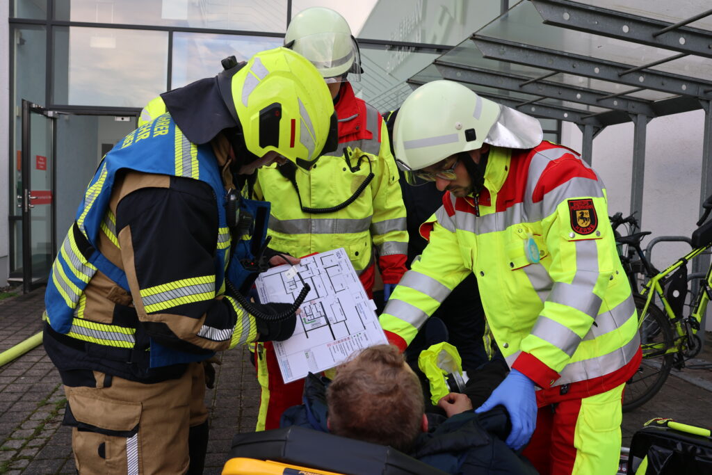 Rettungskräfte mit einem der geretteten Schauspieler und eine Karte vom Gebäude.