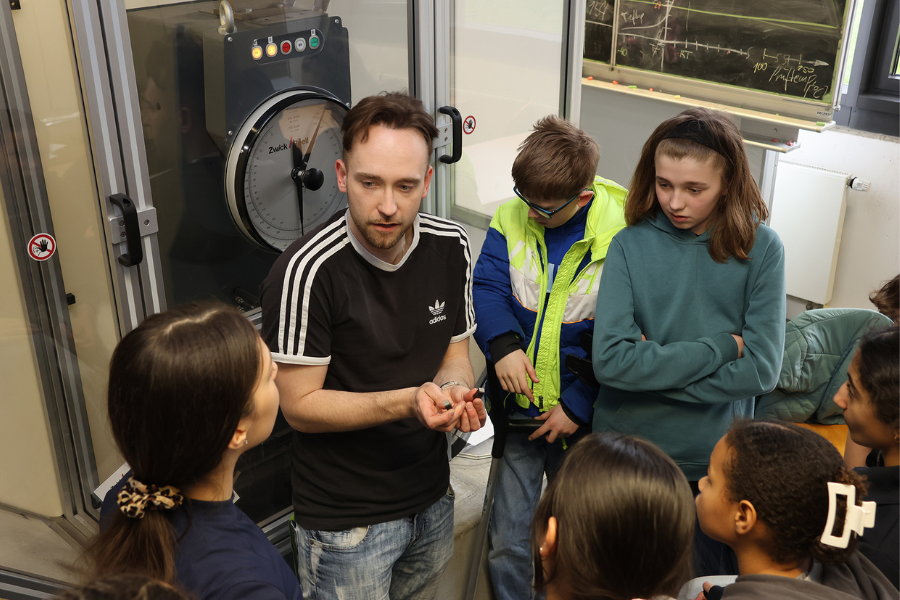 Hochschul-Mitarbeiter Vito Burgio erklärt den Schüler:innen die Werkstoffprüfung